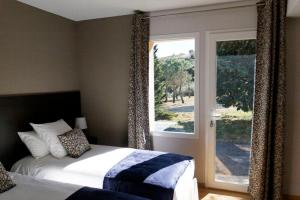 - une chambre avec un lit et une grande fenêtre dans l'établissement Les Villas du Château de Lastours, à Portel-des-Corbières