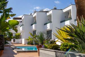 a large white building with a swimming pool and plants at Apartamentos La Tegala in Puerto del Carmen