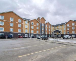 un grand bâtiment avec des voitures garées dans un parking dans l'établissement Quality Inn & Suites, à Estevan