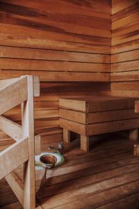 a sauna with a wooden wall and a bowl on the floor at Kevade Guesthouse with Sauna in Kuressaare