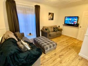 a person sitting on a couch in a living room at EasyRest Spalding - 4 Beds & Free Parking - Central & Modern Open Plan Apartment - Convenient Location in Spalding