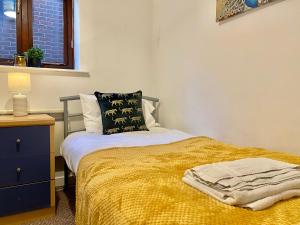 a bedroom with a bed with a yellow blanket at EasyRest Spalding - 4 Beds & Free Parking - Central & Modern Open Plan Apartment - Convenient Location in Spalding
