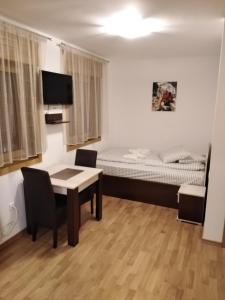 a small room with a bed and a table and chairs at Apartmani Šarm in Zlatibor