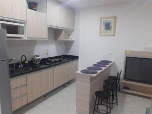 eine Küche mit einer Theke mit Stühlen und einem TV in der Unterkunft flat gavim in Olímpia