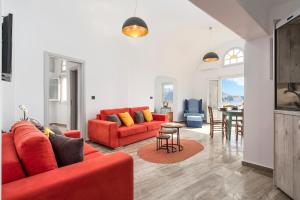 a living room with a red couch and a table at Sole d'oro Sunset & Caldera View Grand Suite in Oia