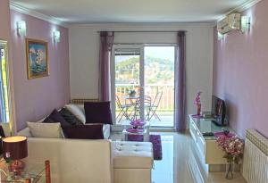 a living room with a couch and a large window at Apartment Siesta in Cavtat