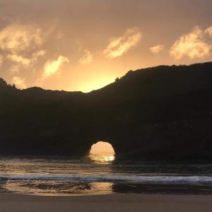 una puesta de sol sobre un cuerpo de agua con una montaña en Cottages20, en Coffee Bay