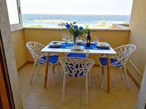 una sala da pranzo con tavolo, sedie e finestra di Bilocale Punta Rosa - Fronte Spiaggia a Otranto