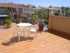 3 sillas blancas y una mesa en el patio en Pensión Egea II, en Puerto de Mazarrón