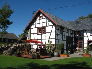 een wit en zwart huis met een tafel en een paraplu bij Lehmlounge in Monschau