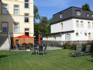 une cour avec des chaises et une table en face d'un bâtiment dans l'établissement Pension Kreisel, à Bad Kösen