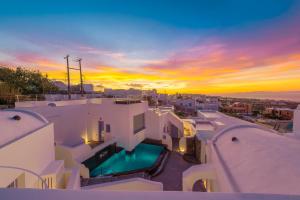 a sunset over a villa with a swimming pool at Sole d'oro Luxury Suites in Oia
