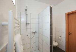 La salle de bains blanche est pourvue d'une douche et de toilettes. dans l'établissement Backerwirt - Wohnen und Schlafen, à Welden