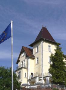 a tall building with a flag in front of it at Hotel & Restaurant Bergschlösschen in Buckow