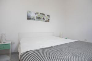 a white bedroom with a bed and a picture on the wall at Villetta Emma in Torre Lapillo