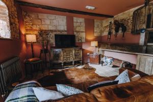 ein Wohnzimmer mit einem Sofa und einem TV in der Unterkunft The Gin Trap Inn in Ringstead