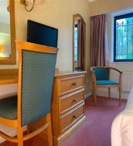 a bedroom with a dresser with a tv on top of it at Fairways Lodge & Leisure Club in Manchester