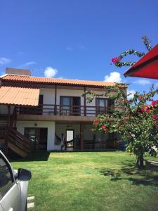 ein Haus mit einem grünen Hof mit einer Person, die davor steht in der Unterkunft Casa do Francês Temporada in Maceió