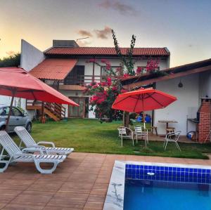 a house with chairs and umbrellas and a swimming pool at Casa do Francês Temporada in Marechal Deodoro