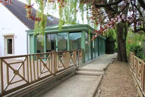 ein Haus mit einer grünen Veranda mit einem Baum in der Unterkunft Logis Lhôtel Restaurant Antony Verrières Le Buisson in Verrières-le-Buisson