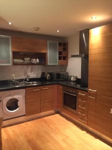 a kitchen with wooden cabinets and a washing machine at Leeds Dock Apartment in Leeds