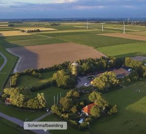 an aerial view of a windmill and a field with wind turbines at Het Lage Noorden in Marrum
