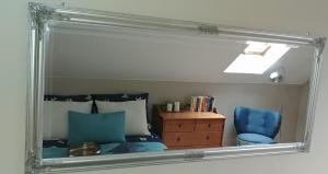 a mirror reflecting a bedroom with a bed and a blue chair at Apartamenty NOVA na Krakowskiej No 2 in Bielsko-Biala