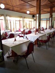 une salle à manger avec des tables blanches et des chaises rouges dans l'établissement KING'S CONFERENCE CENTRE, à Bujumbura