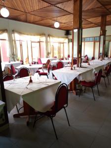 a dining room with white tables and red chairs at KING'S CONFERENCE CENTRE in Bujumbura
