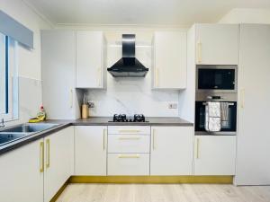 a white kitchen with white cabinets and a sink at Cardonald Central in Glasgow