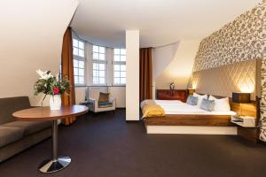 Habitación de hotel con cama y sofá en Royal International Leipzig, en Leipzig