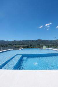 a swimming pool with blue water and mountains in the background at Cabaña Modestita - FINCA PUDUAM in Villa General Belgrano