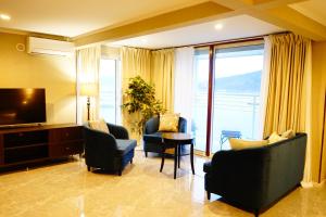 ein Wohnzimmer mit Stühlen, einem TV und einem Tisch in der Unterkunft HOTEL HIMALAYA SEA in Ito