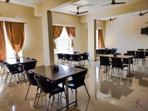 una sala da pranzo con tavoli, sedie e finestre di Fortune Village Hotel a Kundapur
