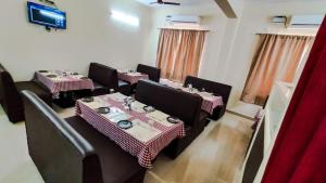 una sala da pranzo con tavoli, sedie e TV di Fortune Village Hotel a Kundapur