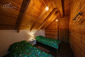 una camera con due letti in una stanza con soffitti in legno di Chata że HEJ a Bukowiec