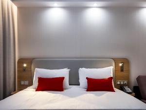 łóżko z 2 czerwonymi poduszkami w pokoju w obiekcie Holiday Inn Express - Nice - Grand Arenas, an IHG Hotel w Nicei