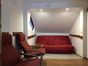 un sofá rojo en una habitación con 2 sillas en Pension Green Park, en Brasov