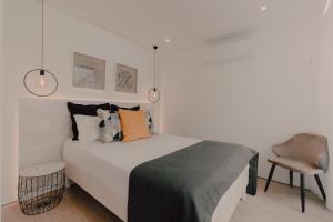 um quarto branco com uma cama e uma cadeira em Home at Azores - Oasis House em São Roque