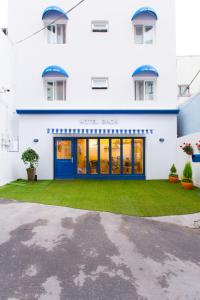 a white building with a blue door and a green yard at Hotel Gaon Seoul Dongdaemun in Seoul