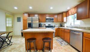 Una cocina con gabinetes de madera y una isla con taburetes de bar. en 1014_Swope, en Colorado Springs