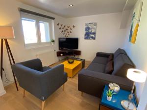 uma sala de estar com dois sofás e uma televisão em DUPLEX Le 12 - Appartement avec terrasse dans le vignoble - 5 mn du centre de Colmar em Wettolsheim