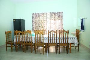 a dining room table with wooden chairs and a window at Aminvilla resort - family stay to explore Sylhet in Sylhet