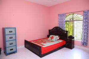a bedroom with pink walls and a bed and a dresser at Aminvilla resort - family stay to explore Sylhet in Sylhet