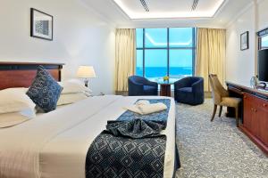 um quarto de hotel com uma cama, uma secretária e uma televisão em Crown Tower Hotel em Al Jubail
