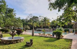 a yard with a fountain and a swimming pool at Hotel Puerta Chichen in Chichén-Itzá