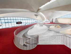 a spiral staircase in an airport with red carpet at TWA Hotel at JFK Airport in Queens