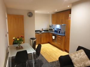 a kitchen with wooden cabinets and a table with chairs at Birmingham Diamond, 2 bedroom Apartment in Birmingham