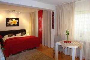 Un dormitorio con una cama roja y una mesa con una flor. en Parkresidenz Hotel Garni, en Bad Abbach