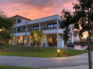 a white building with a sunset in the background at Bachhof Resort Hotel in Kirchroth